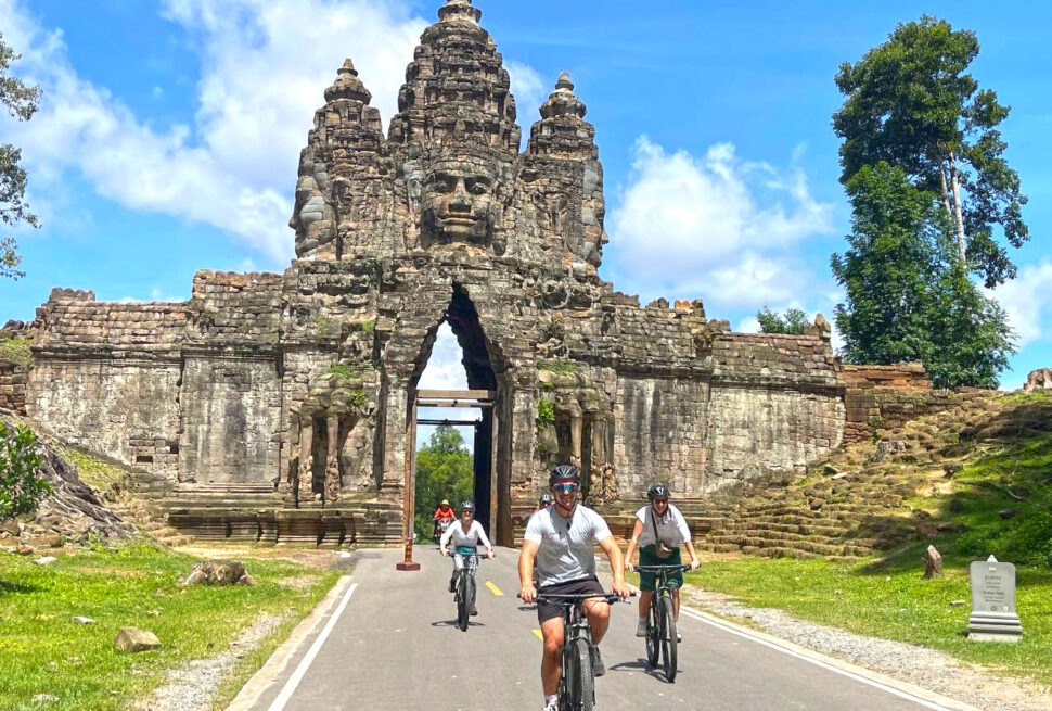 Cycling through the south gate of Angkor Thom with family tour