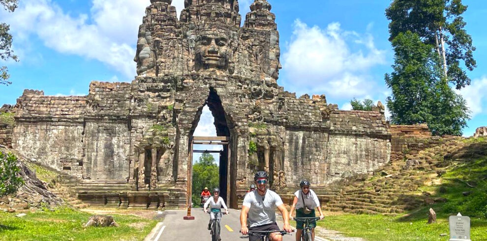 Cycling through the south gate of Angkor Thom with family tour